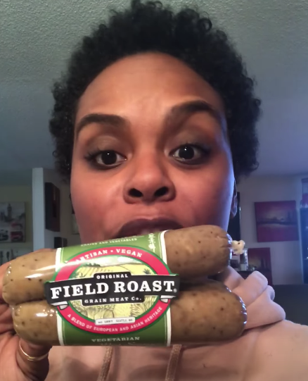 Tabitha holding up a package of meat-free, vegan sausage
