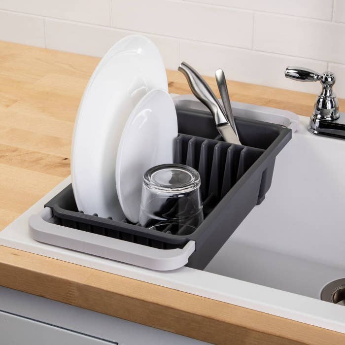 the grey dish rack over a sink with a few dishes inside