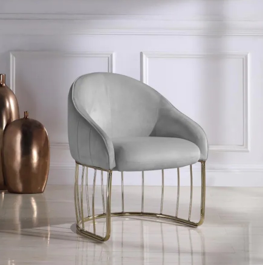 A grey velvet accent chair with a gold, half moon metal frame