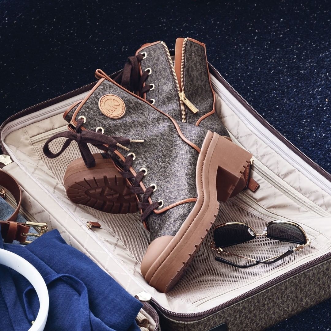 The boots inside a suitcase next to a pair of sunglasses