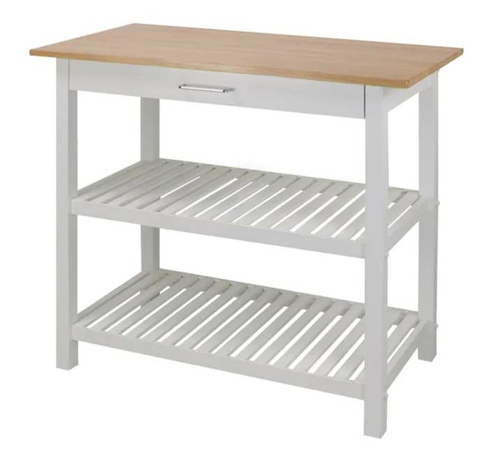 A white wood two-tier kitchen island with a cutting board counter top and one drawer