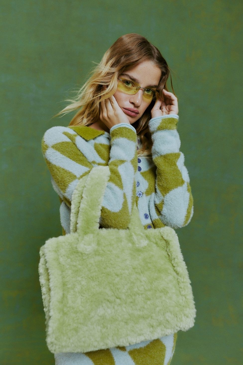 model holding a light green faux fur tote bag