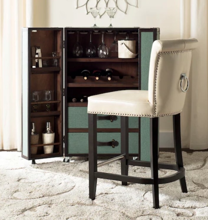 A cream upholstered bar stool with silver nailhead accent and a metal ring on the back