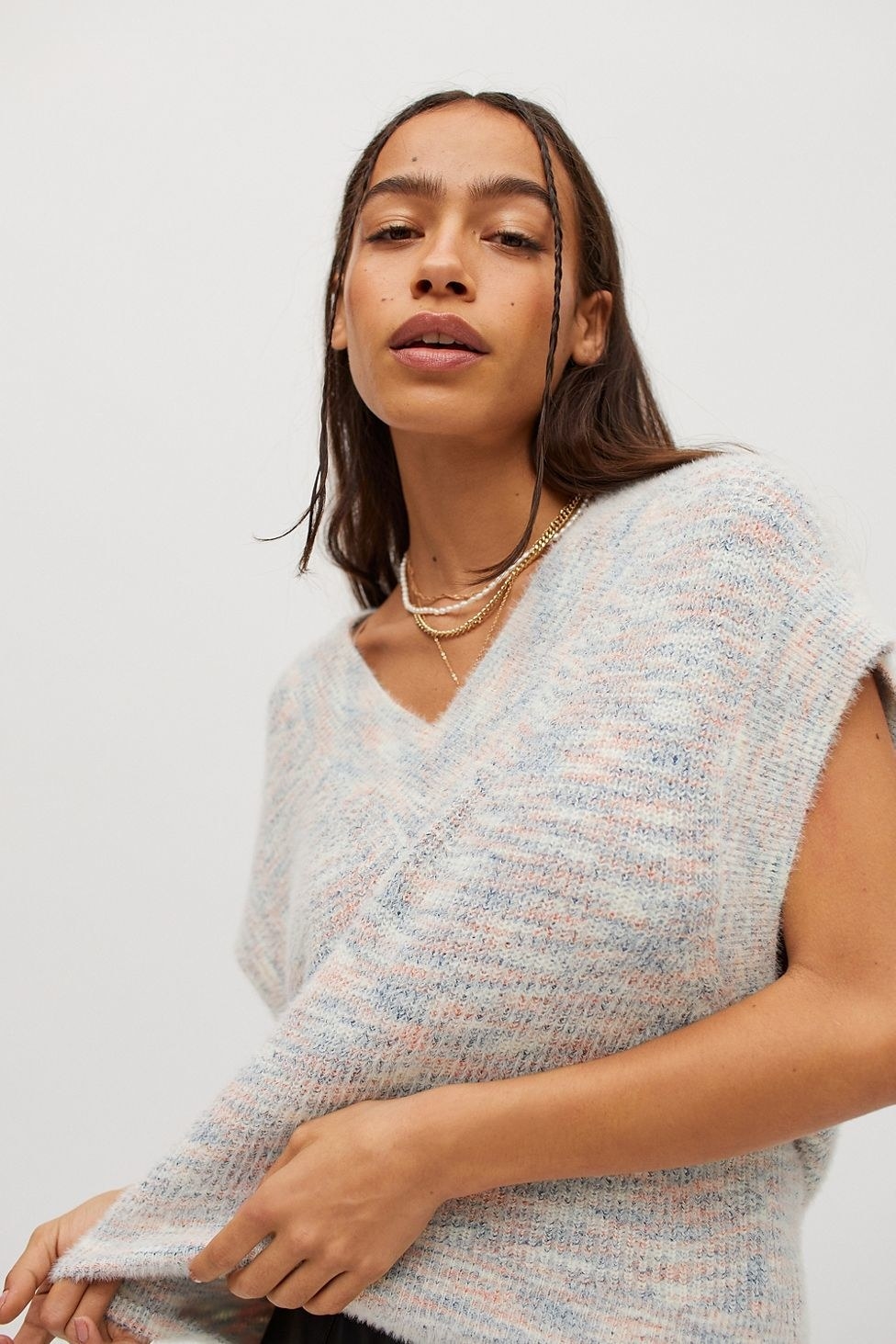 model in a light white, pink, and blue sweater vest