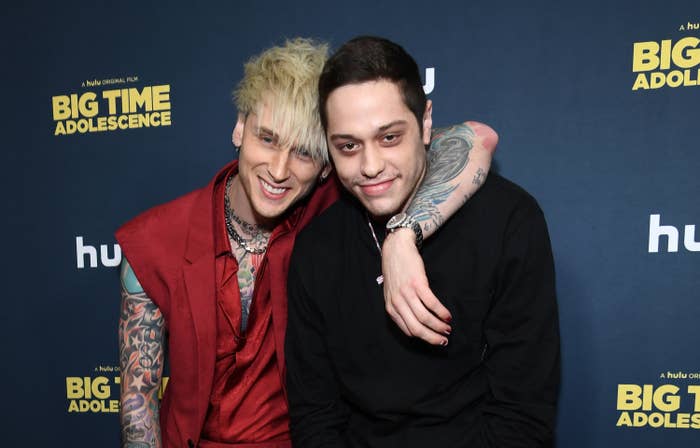 MGK smiles as he puts his arm around Pete as the stand on the red carpet at an event