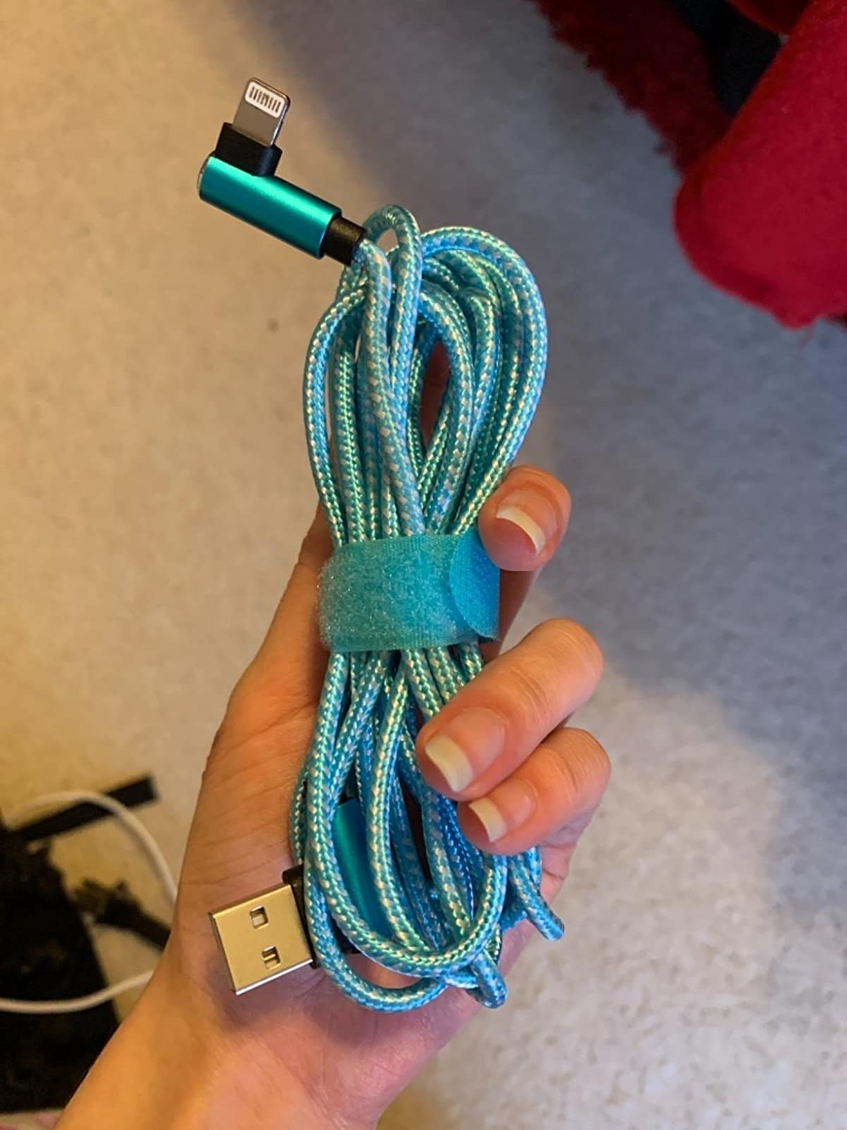 Reviewer is holding a blue cell phone code wrapped up with a velcro cord organizer