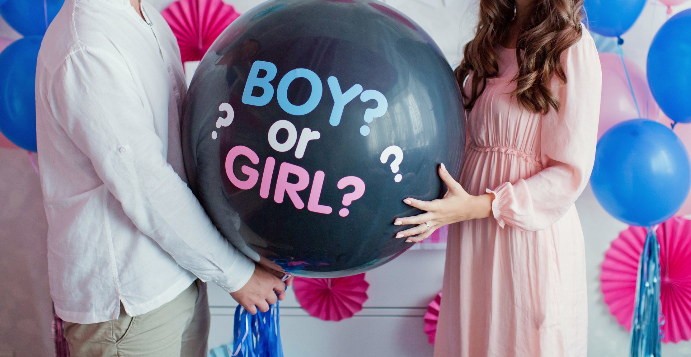 A couple holds a balloon that says, &quot;Boy or Girl&quot; at a gender reveal party