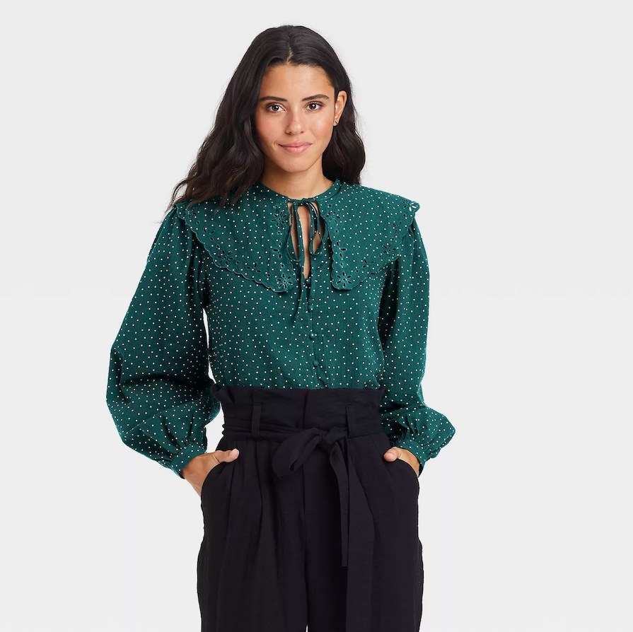 Model wearing green blouse and black pants