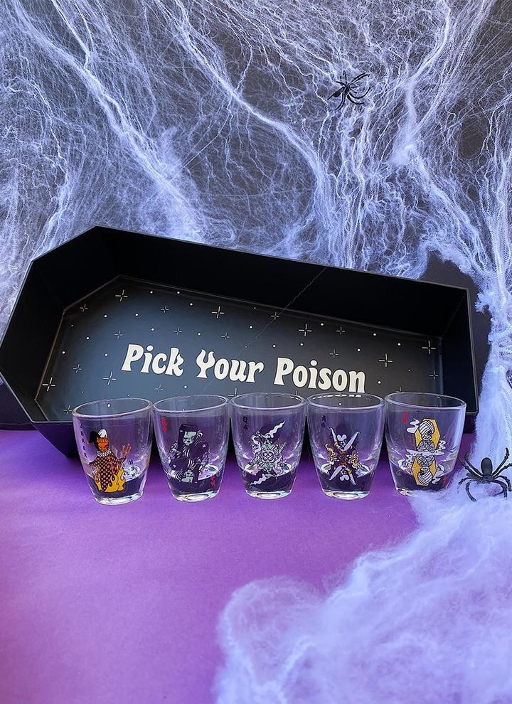 five shot glasses in front of coffin box that says pick your poison