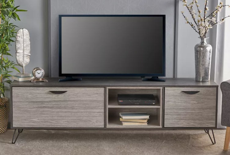 A charcoal gray exterior wooden TV stand with lighter gray textured doors. Has 4 metal hairpin legs to keep it sturdy. One cabinet is twice the size of the other, while an open shelf sits in the middle of the cabinet doors.