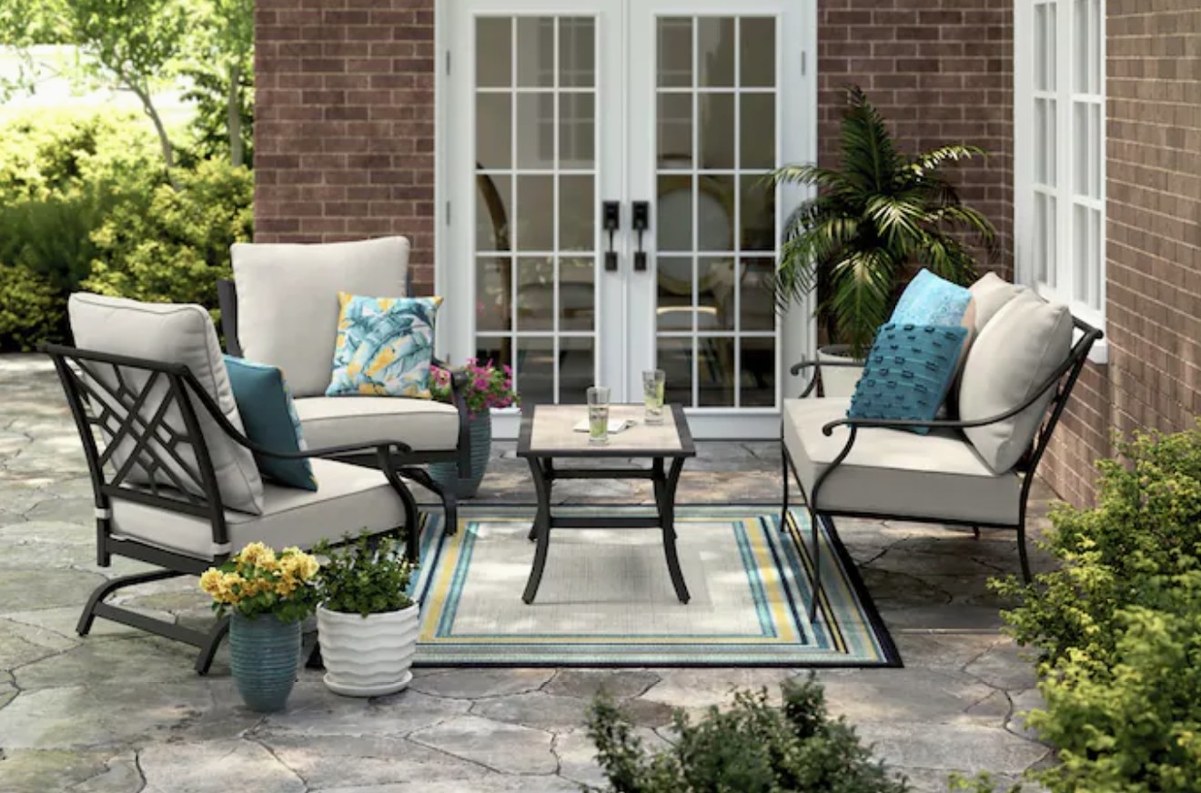 A four piece, cream cushioned/black metal framed patio set with two chairs, one loveseat and one table