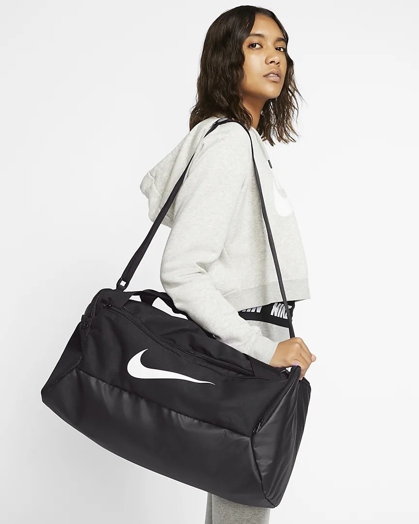 Model wearing white and grey carrying black bag