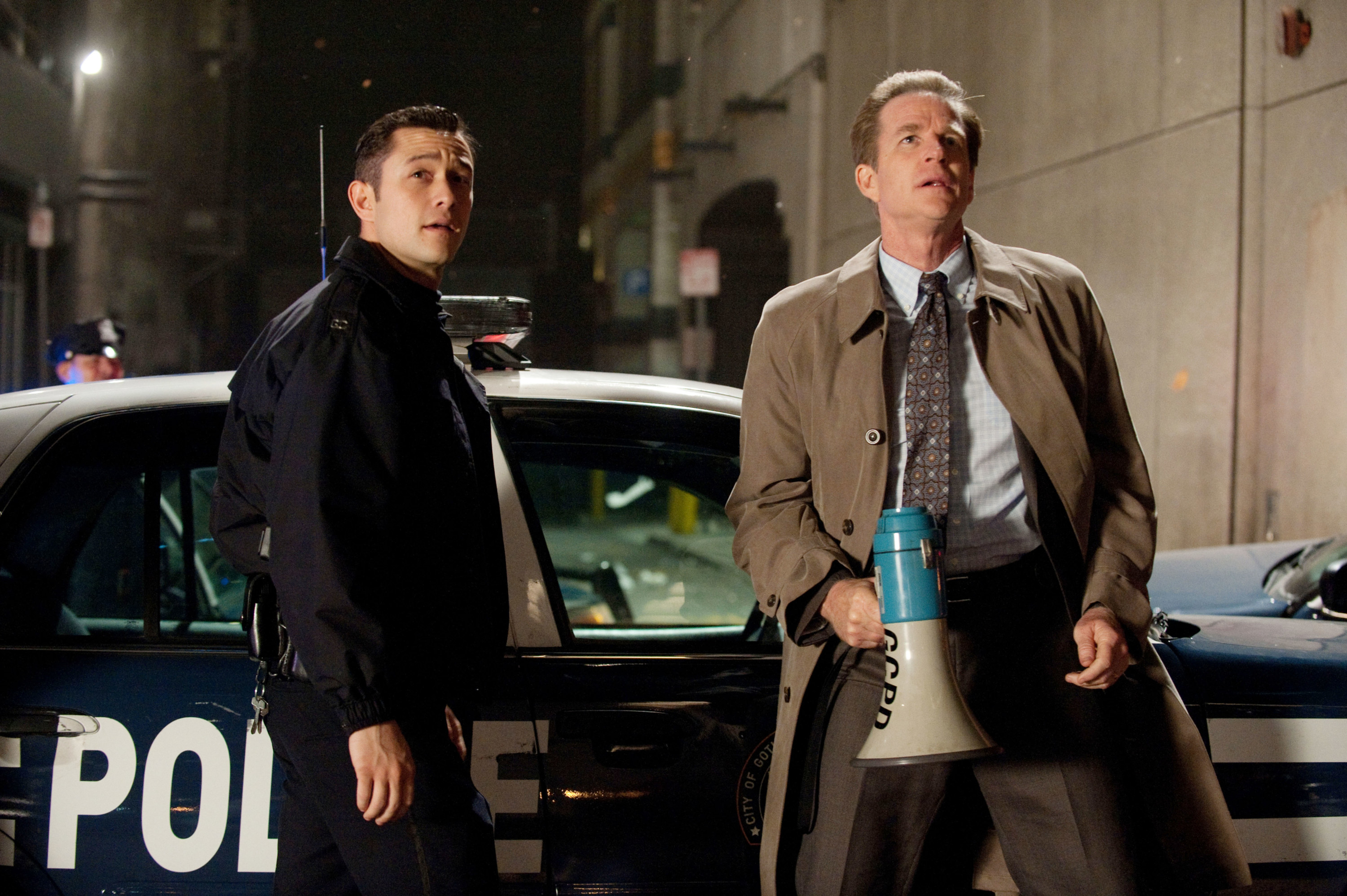 Matthew Modine and Joseph Gordon-Levitt standing in front of a police car