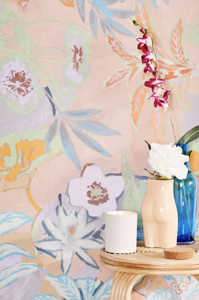 Pastel multicolored flowers on peach wallpaper behind side table with vases