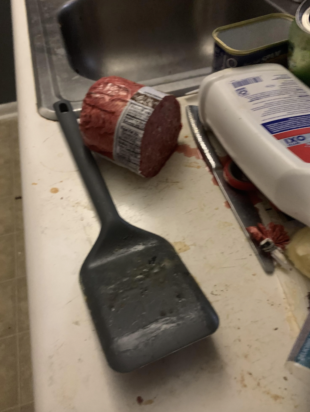 Half of raw ground beef sitting on a dirty kitchen counter
