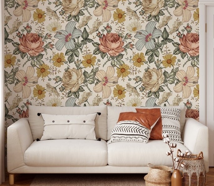 White couch in front of yellow, red, cream, and blue enlarged flower wallpaper