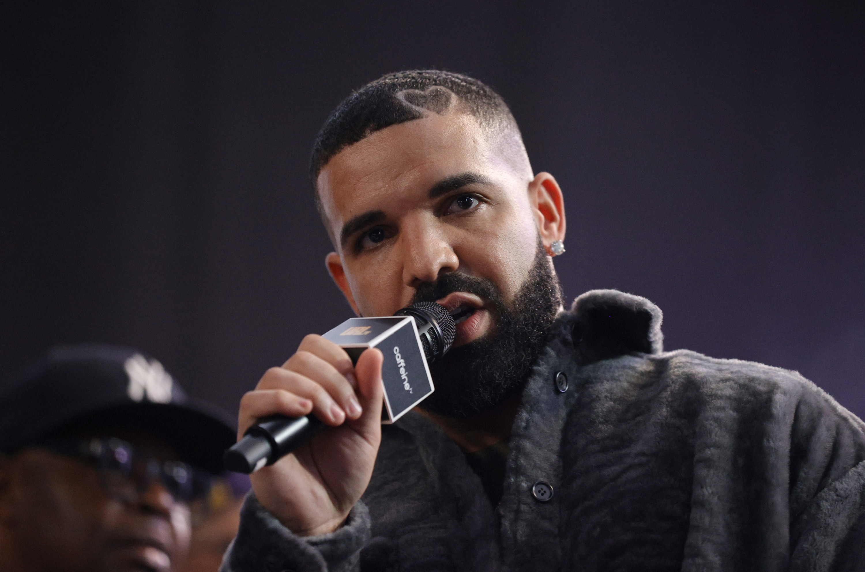 Photo of Drake looking toward the camera holding a microphone