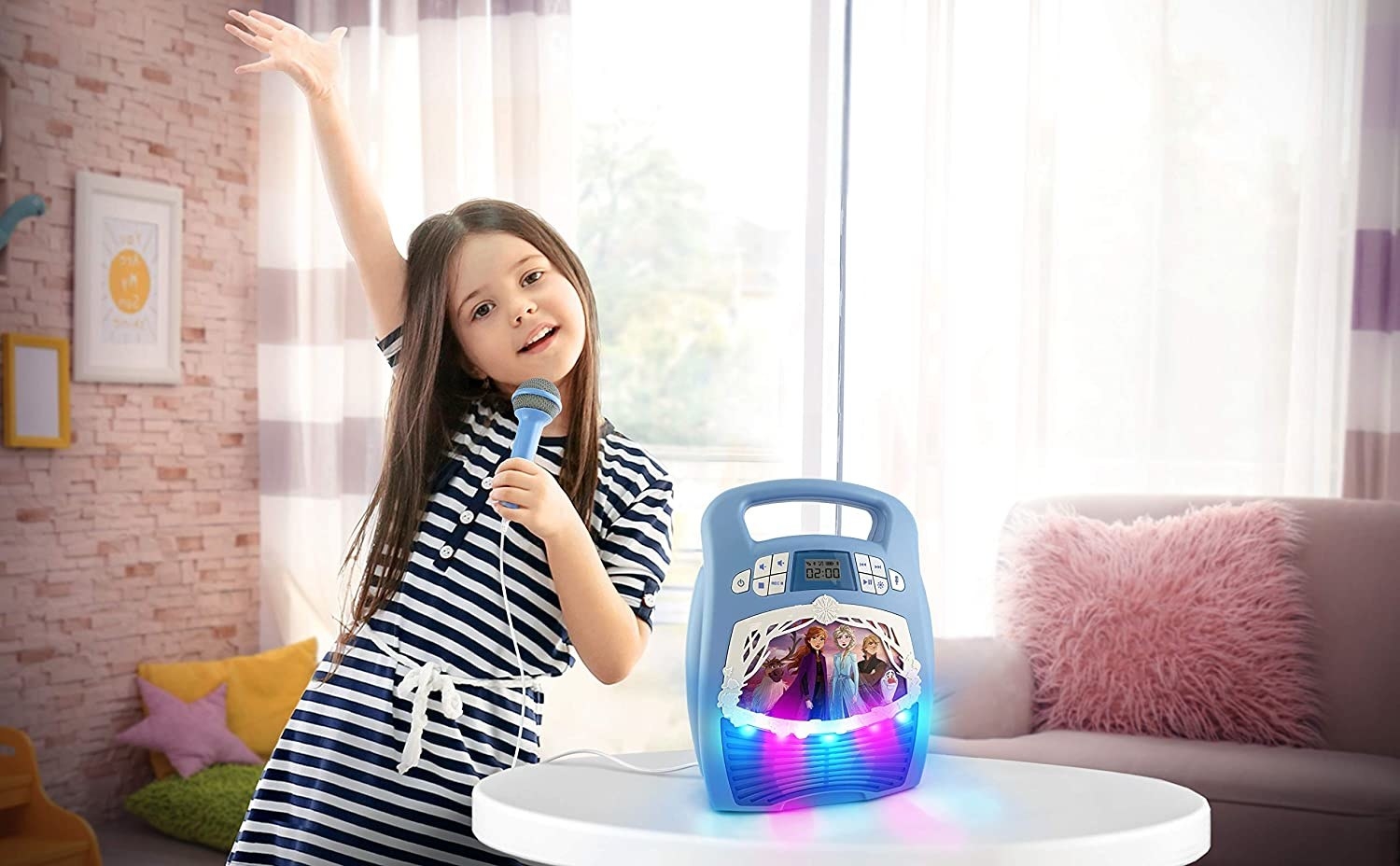 child singing next to blue Frozen 2 Bluetooth Karaoke Machine with LED lights