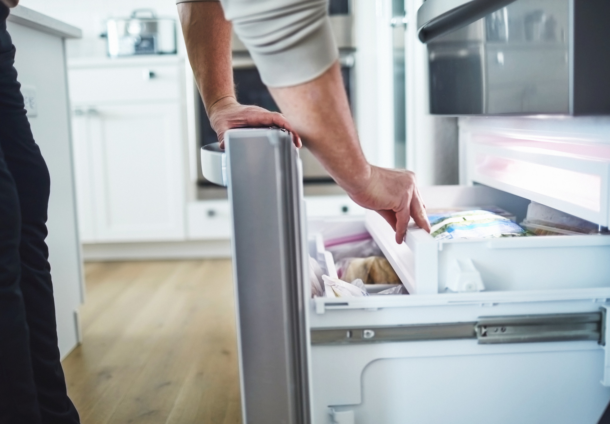 A man reaching into the freezer.