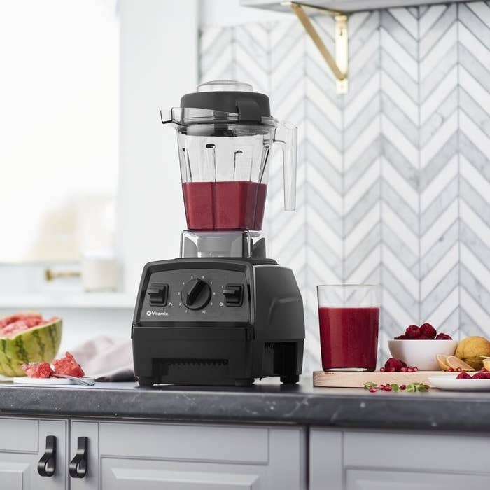 vitamix experian bledner on a counter next to a smoothie and fruit