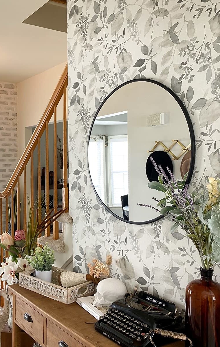 Reviewer image of gray and white floral wallpaper behind brown cabinet with vases