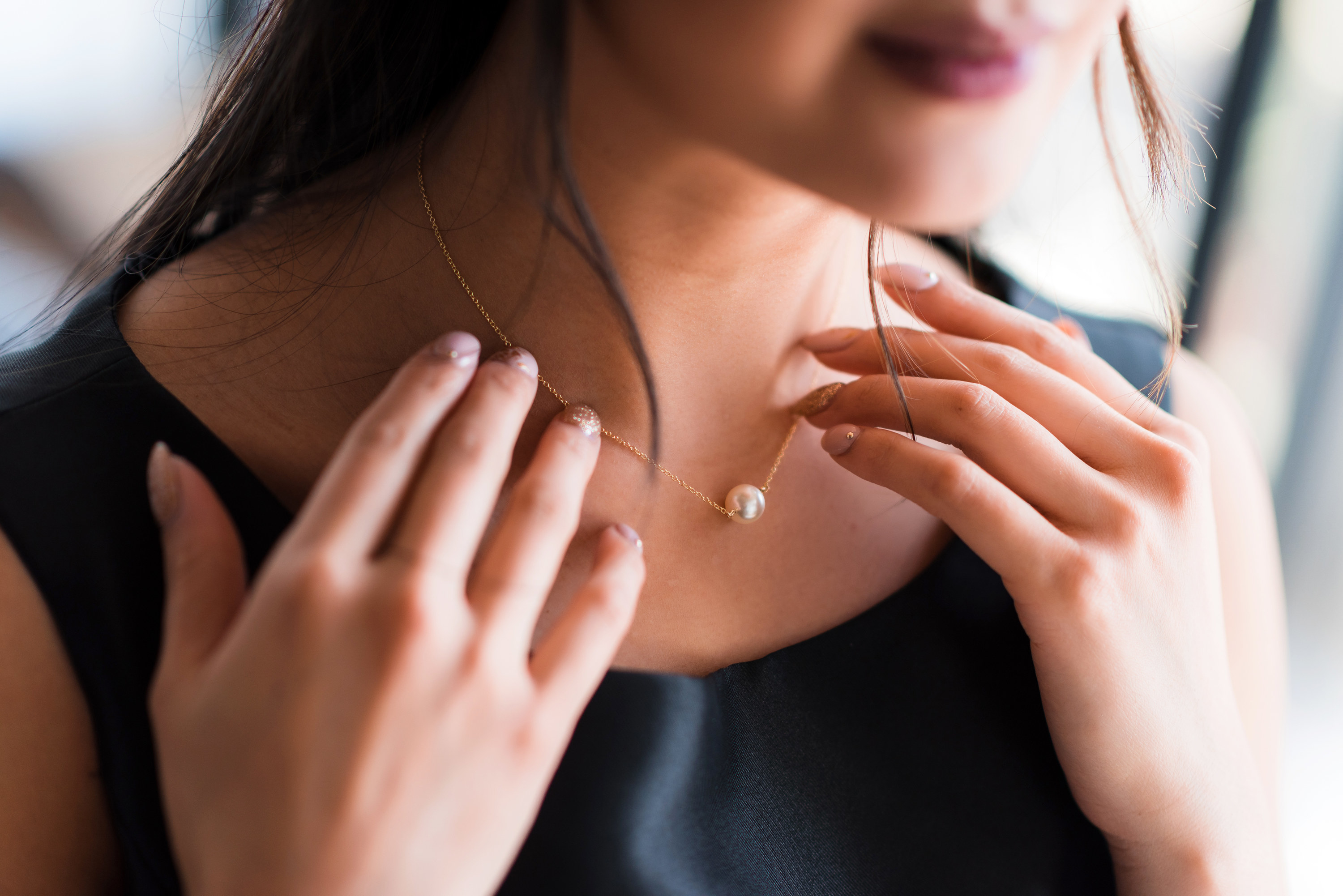 Woman touching pearl necklace around her neck