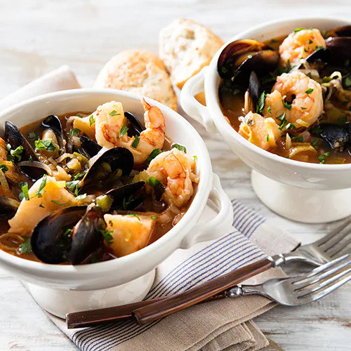 two bowls of Cioppino seafood stew with mussels and shrimp served with a side of bread