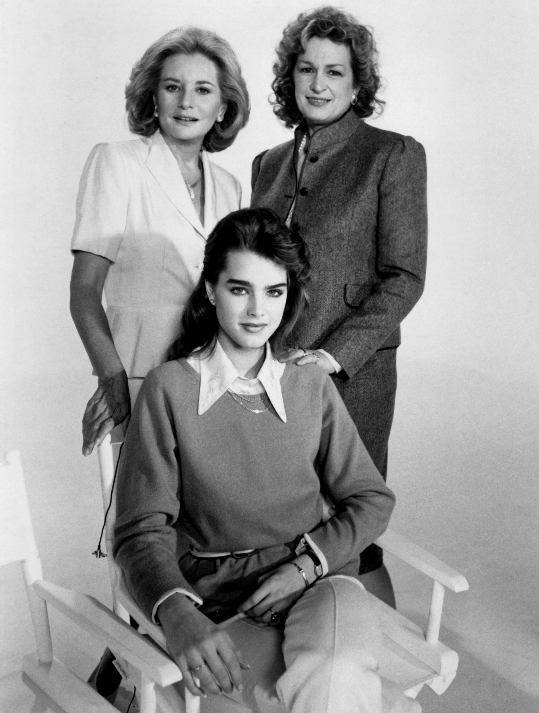 Brooke sits in a chair while Barbara and her mother stand behind her