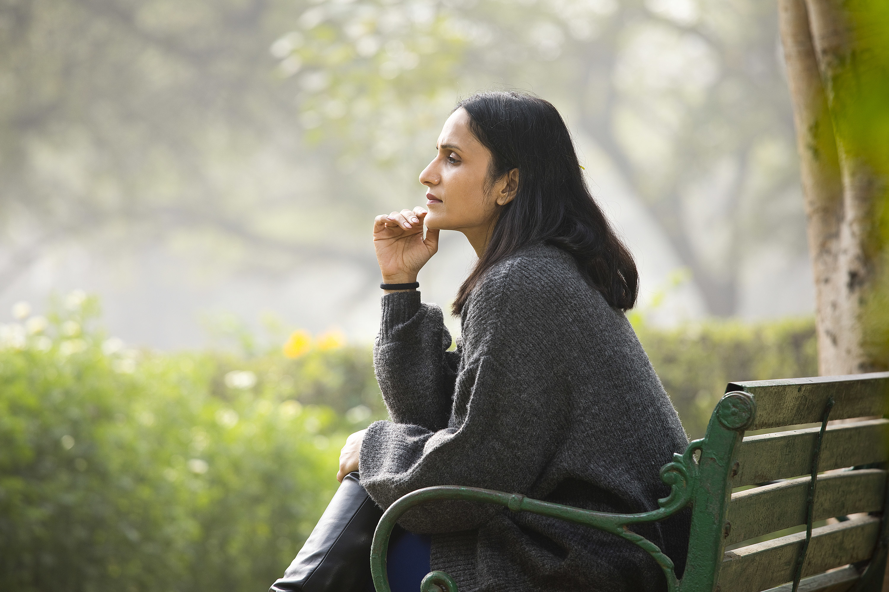 Thoughtful woman sitting on bench at park