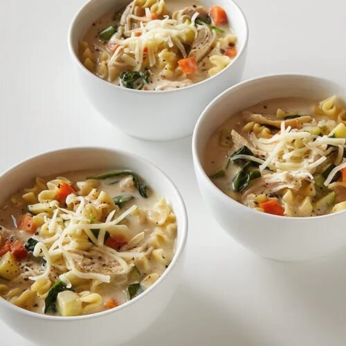 three bowls of white lasagna soup topped with cheese