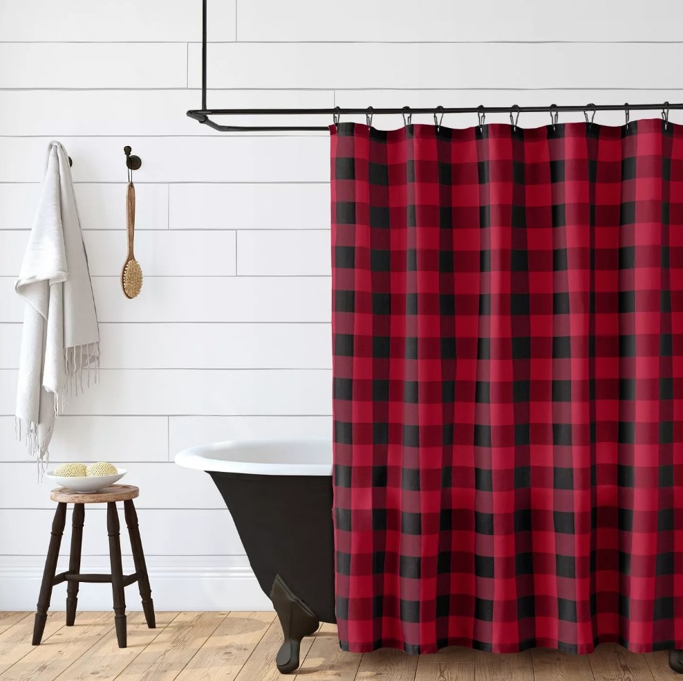Red and black plaid shower curtain hanging over black tub