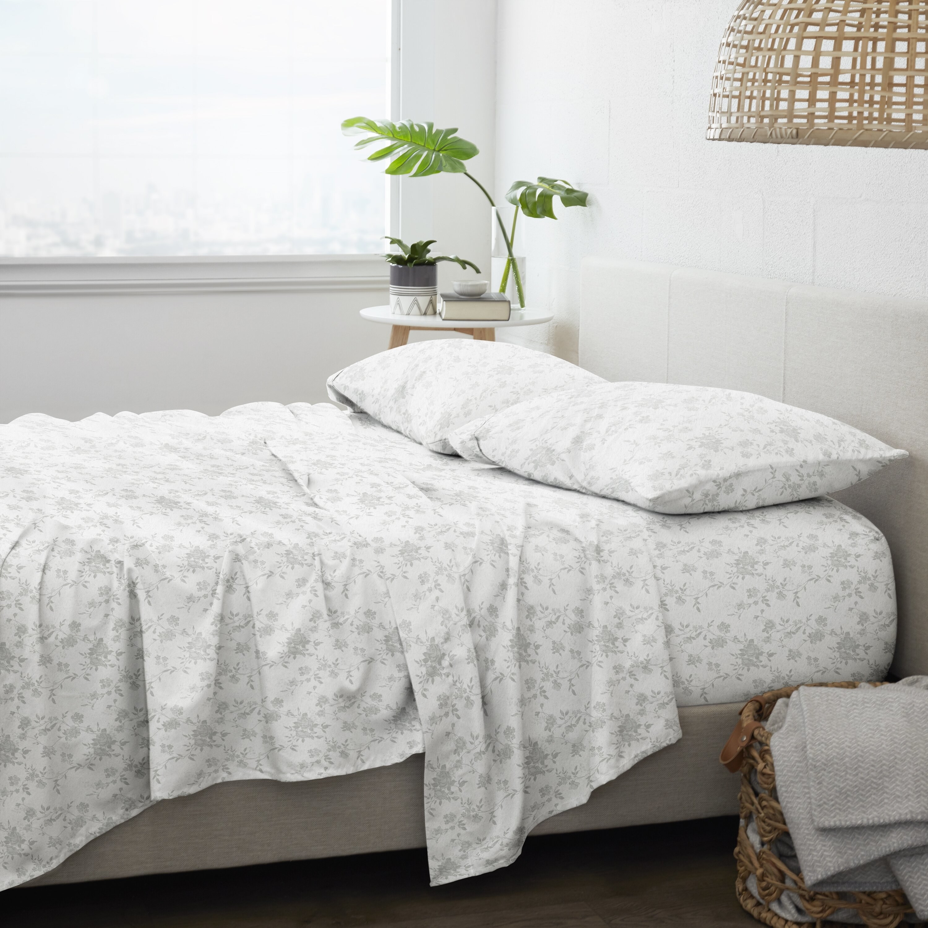 The white and light gray floral sheets on a bed