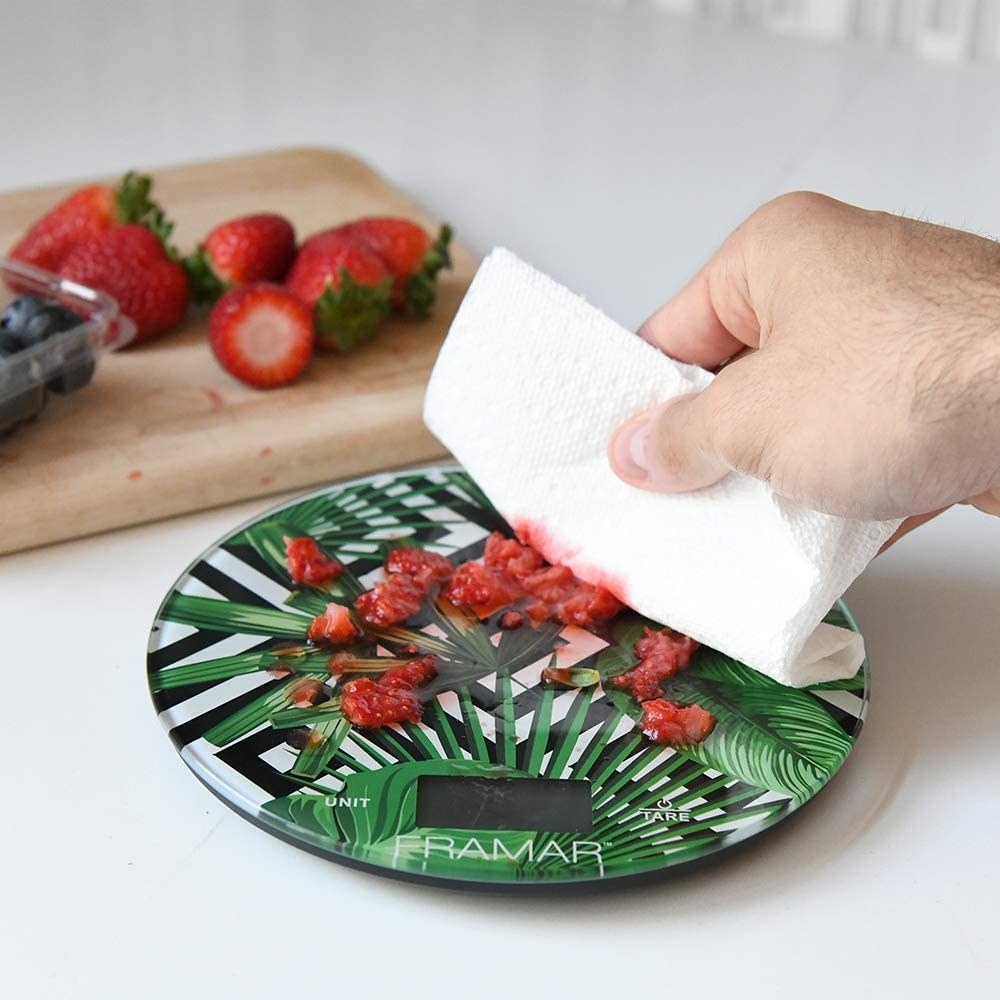 A person wiping strawberry purée off the scale