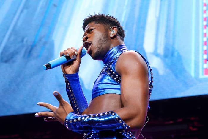 Nas sings into a microphone in a blue metallic outfit