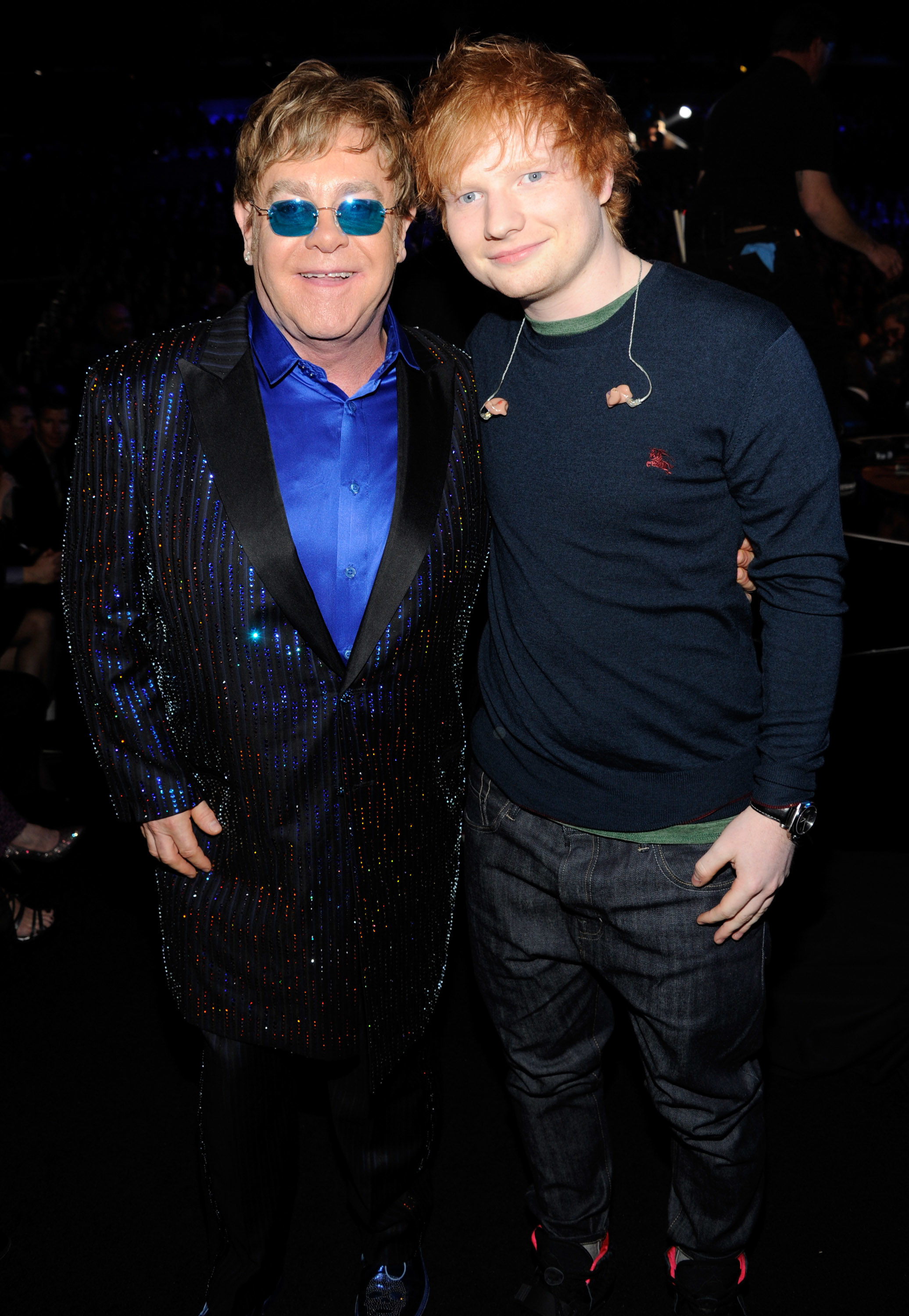 Sheeran poses for a photo with John with earbuds hanging around his neck