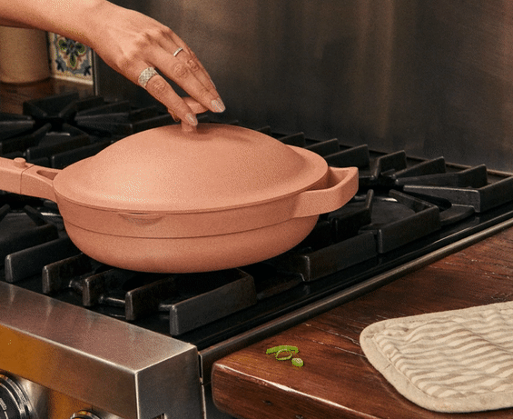 GIF of someone taking the lid off the pink Always Pan and lifting a steamer basket filled with dumplings out of the pan