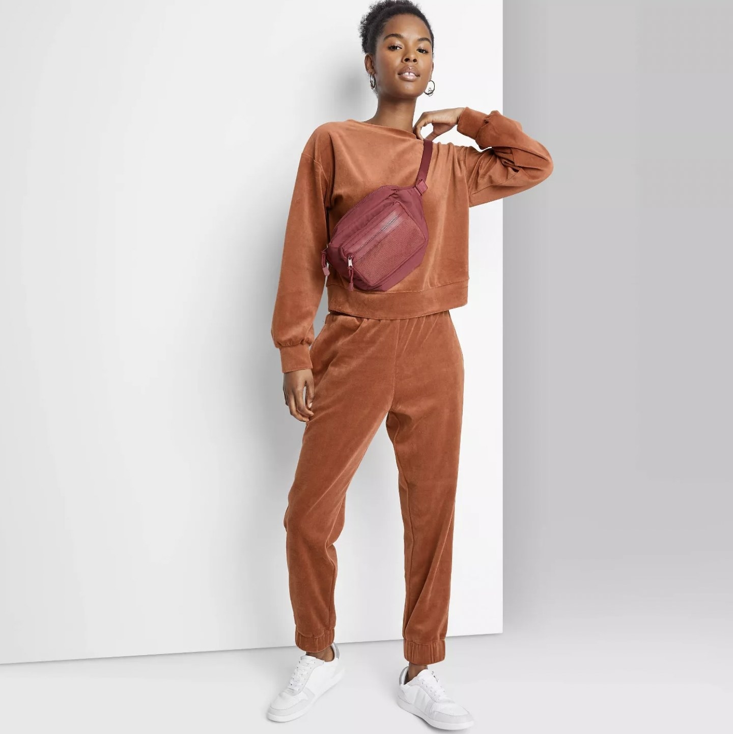 Model in the orange velour joggers with matching long-sleeve sweatshirt