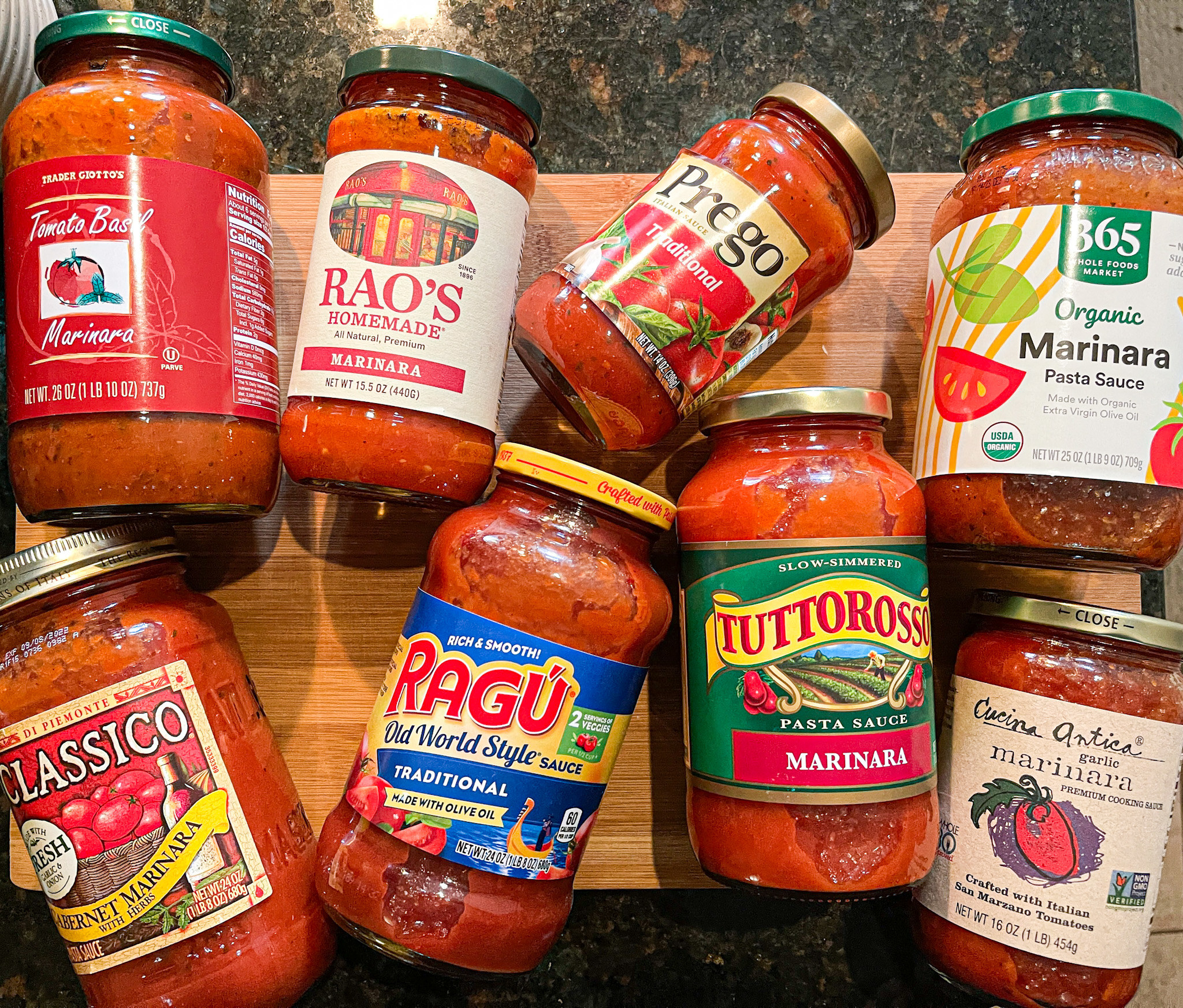 Eight jarred pasta sauces, laid out on a cutting board