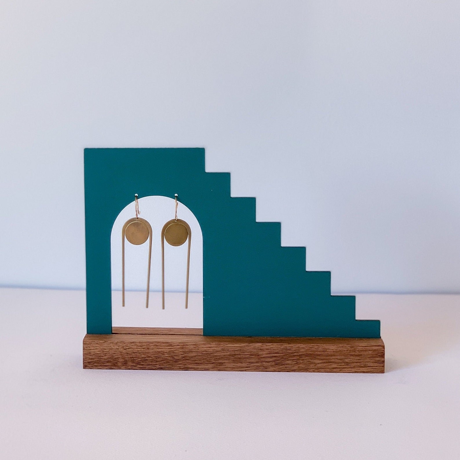 blue stair-like earrings stand with dome-shaped opening for the earrings and wood base