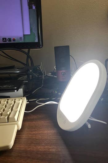 a reviewer photo of the lit lamp sitting on a desk