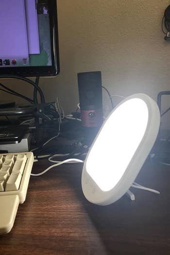 a reviewer photo of the lit lamp sitting on a desk