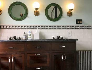 Three wall sconces in a row hanging over a bathroom sink