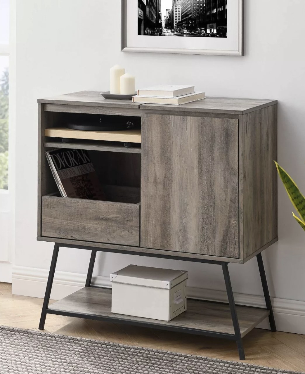 a black and grey media cabinet holding records and a record player