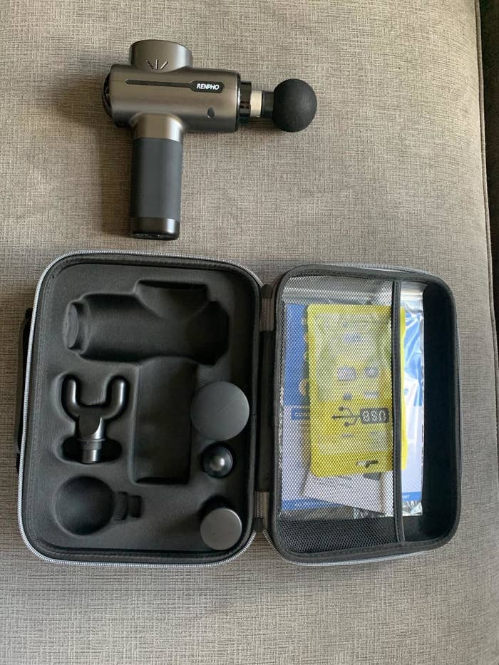 reviewer image of the massage gun, case and the other attachments