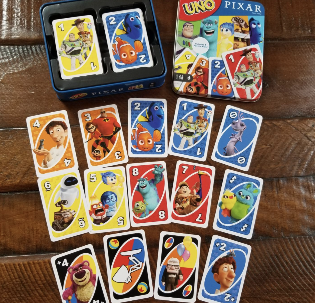 A customer review photo of the deck of Uno cards with characters from ratatouille, finding nemo, the incredibles, up, toy story, and more