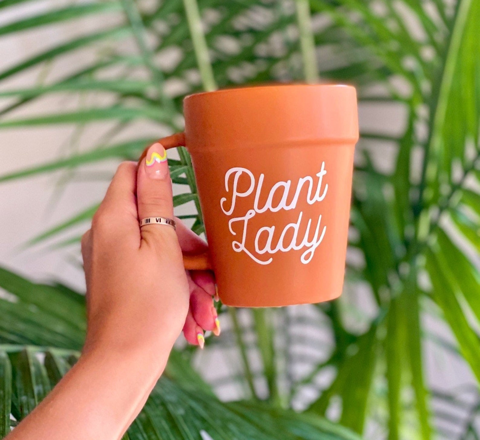 a model holding up the mug that reads &quot;Plant Lady&quot; in white cursive font.