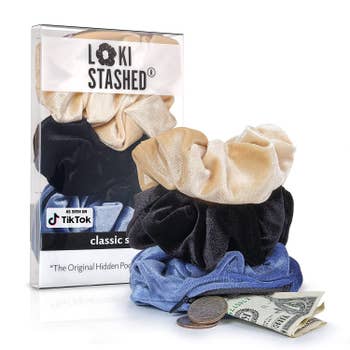 The tan, black, and blue scrunchies stacked on top of one another, with some money coming out of the zip-up pocket on the bottom one