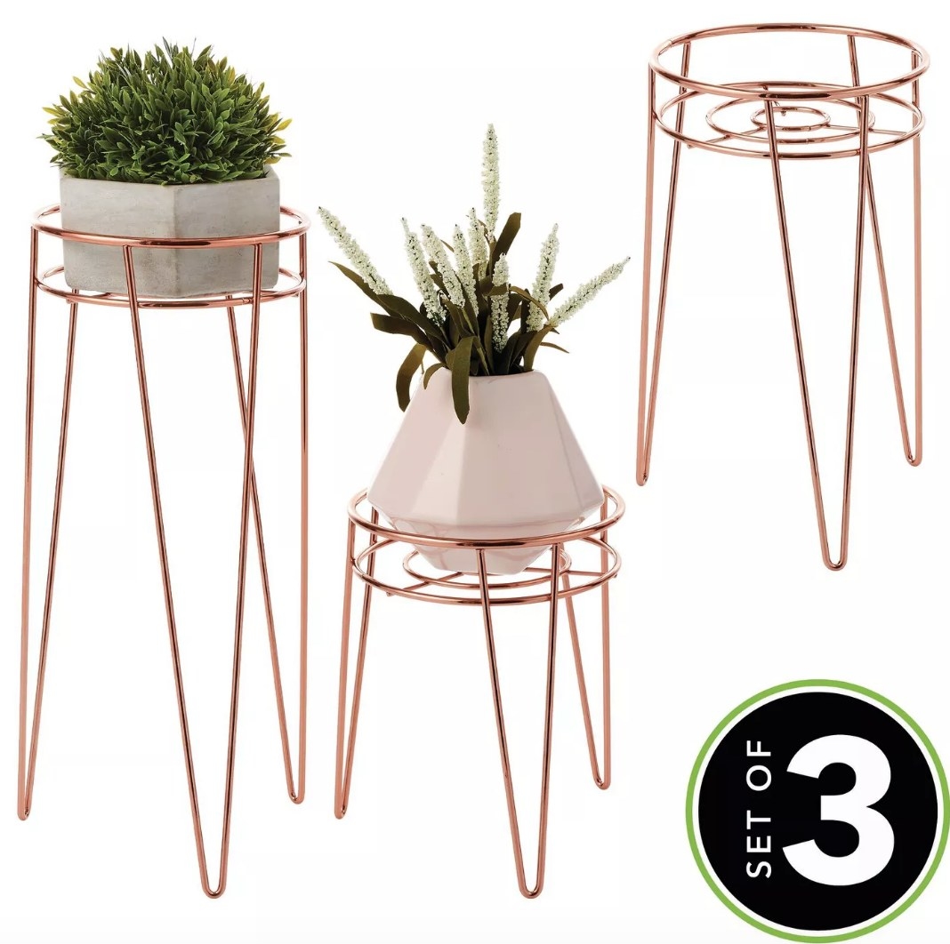 Rose gold wire plant stands, three stands tall one on left with potted plant, short one in middle with potted plant, mid size one on right