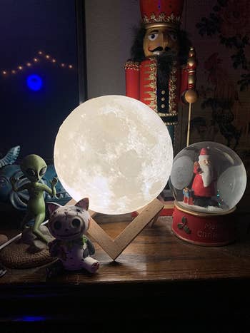 A reviewer image of the moon lamp in a wooden stand on a shelf