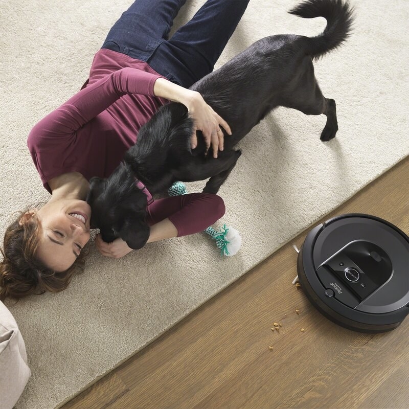 model and dog lying on floor next to an irobot vacuum
